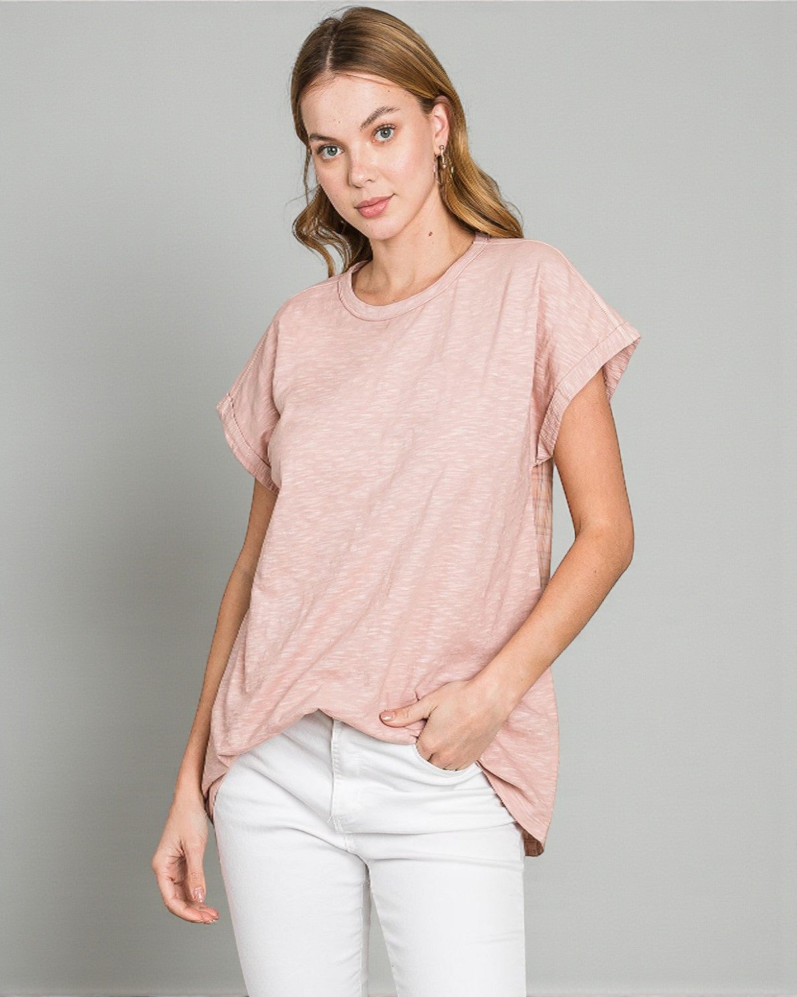 Woman wearing a pink t-shirt and white pants on a gray background