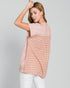 Woman wearing a sleeveless pink and plaid top on a gray background