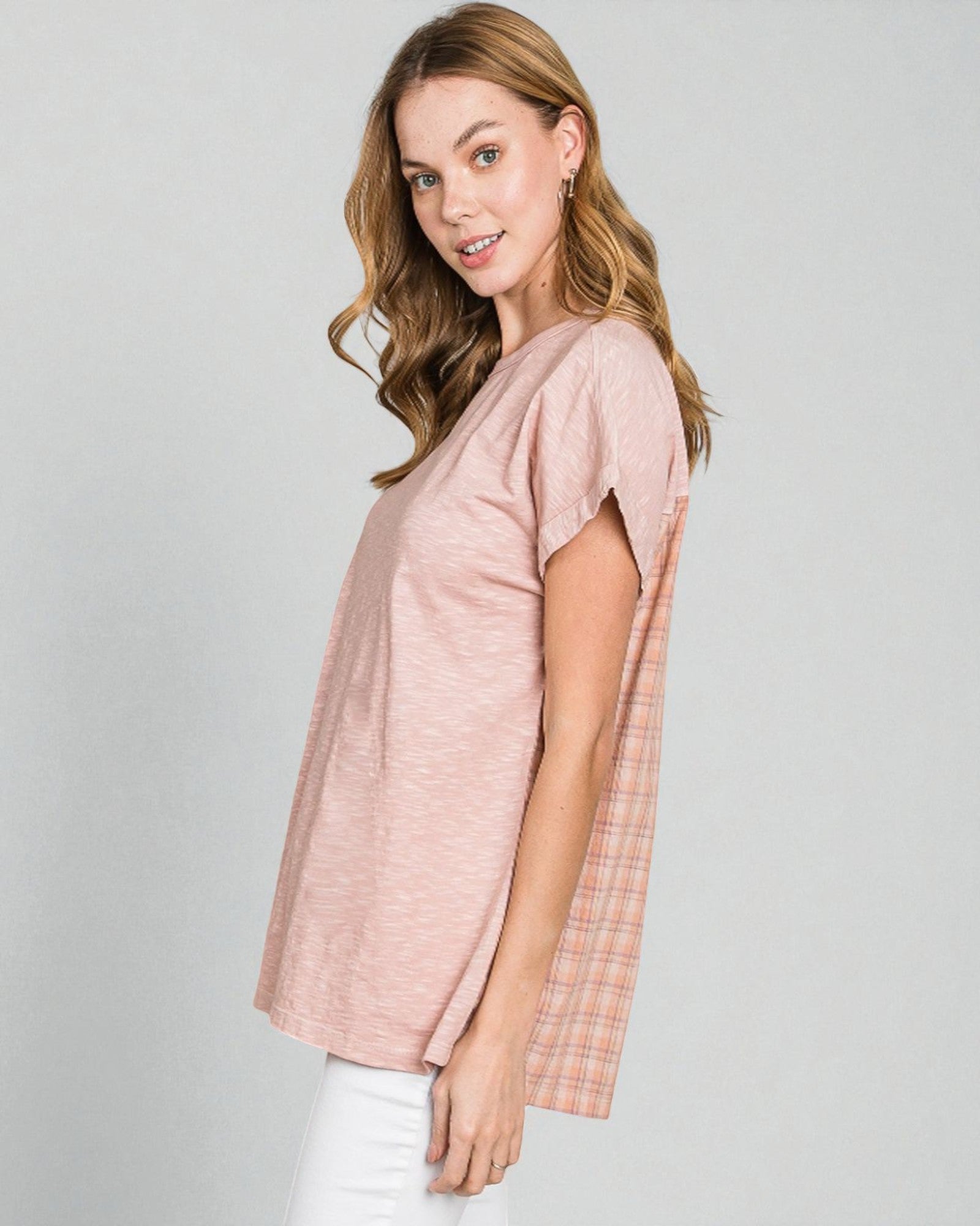 Woman wearing a pink top with a plaid pattern on a gray background