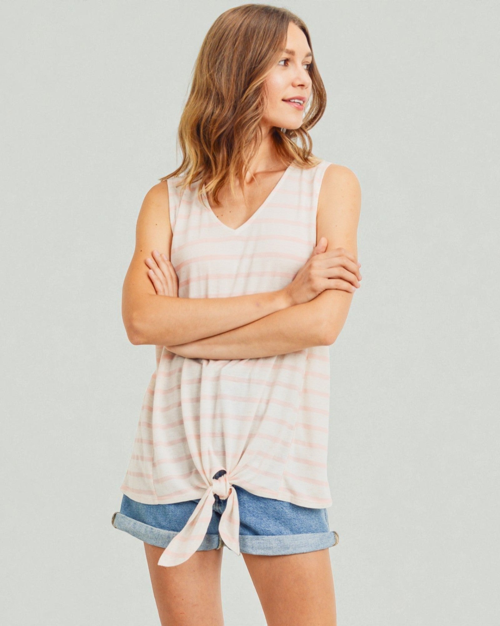 Woman wearing a sleeveless top and denim shorts against a plain background