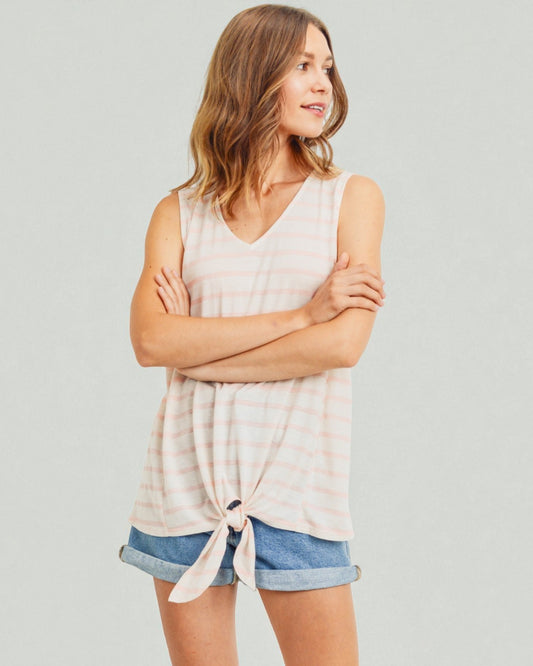 Woman wearing a sleeveless top and denim shorts against a plain background