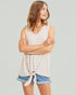 Woman wearing a sleeveless top and denim shorts against a plain background