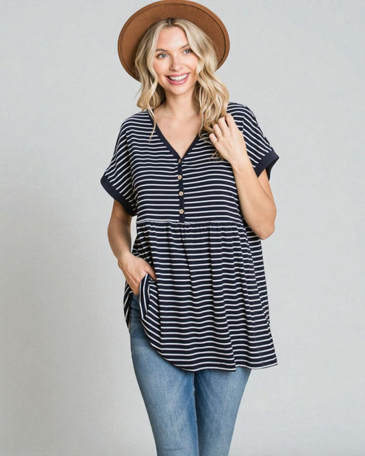 Woman wearing a striped shirt, jeans, and a hat on a plain background