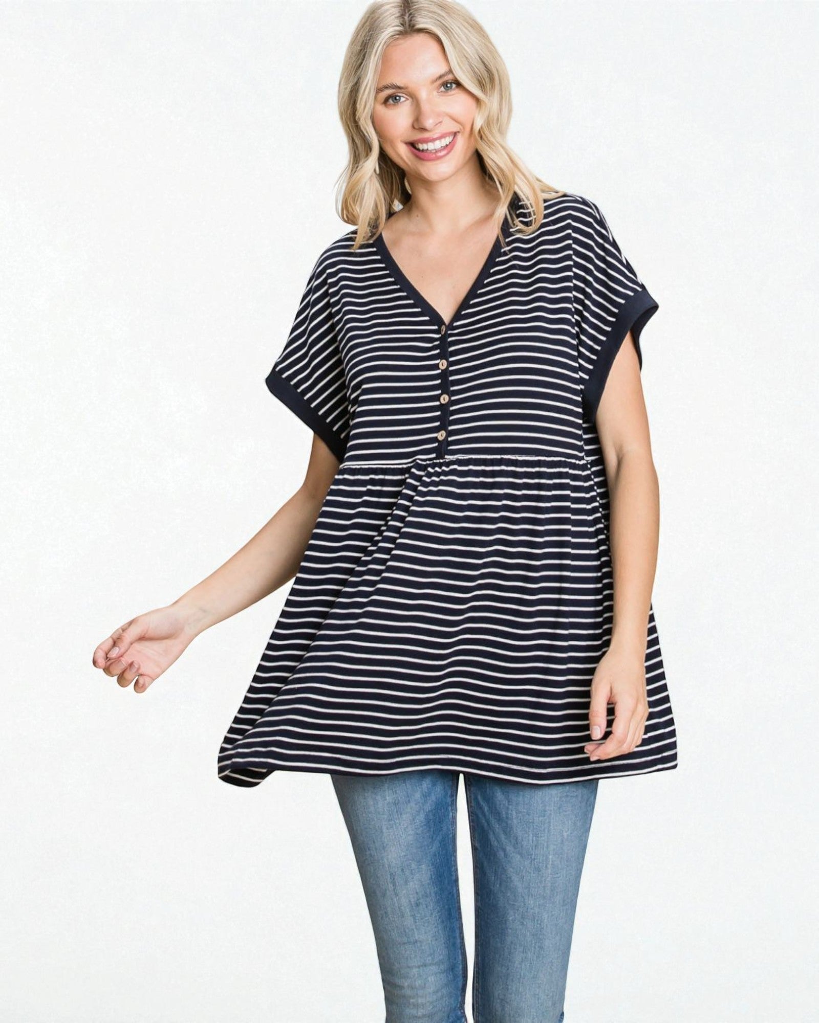 Woman wearing a navy and white striped tunic with blue jeans on a white background