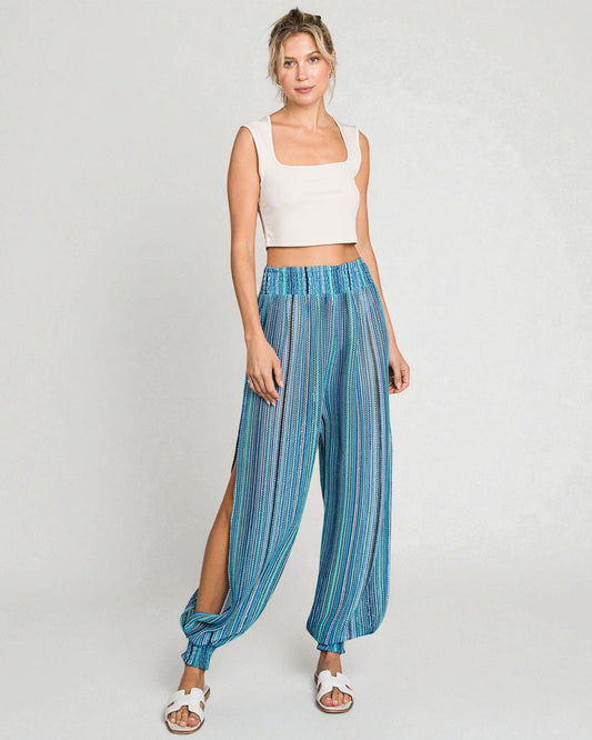 Woman wearing a white top and blue striped pants on a light gray background