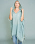 Woman wearing a light blue hooded garment against a gray background