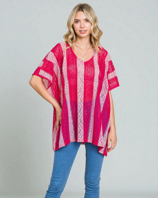 Woman wearing a pink patterned top and blue jeans on a gray background