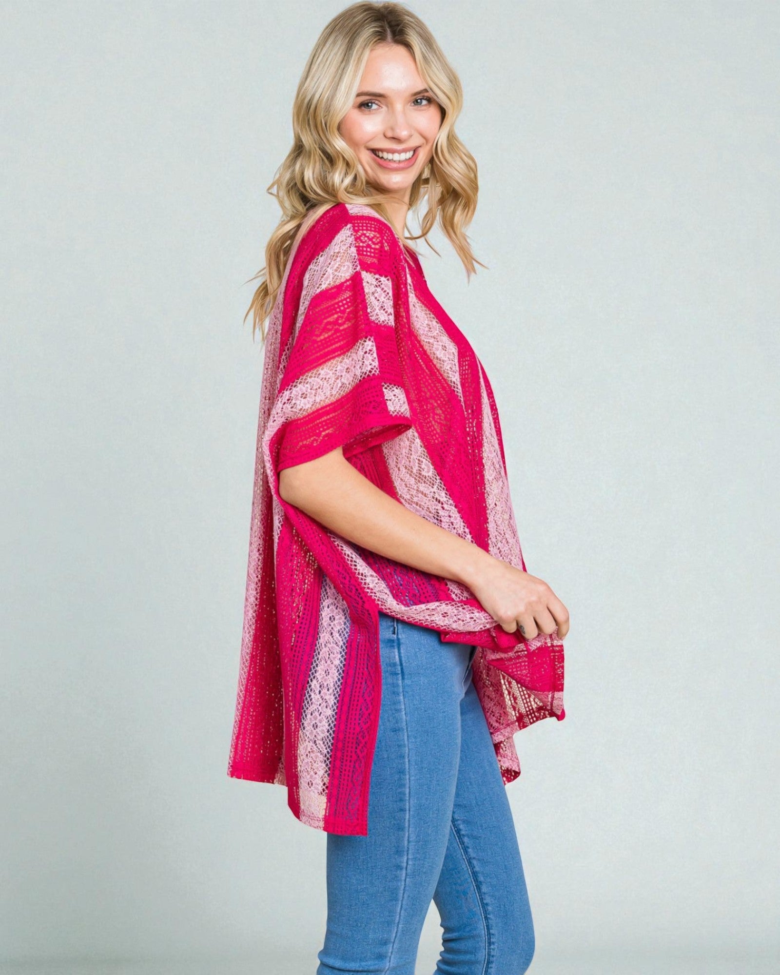 Woman wearing a pink lace poncho over a white background
