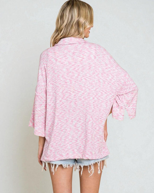 Person wearing a pink patterned shirt and denim shorts on a plain background