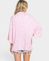 Woman wearing a pink patterned shirt with rolled-up sleeves on a white background