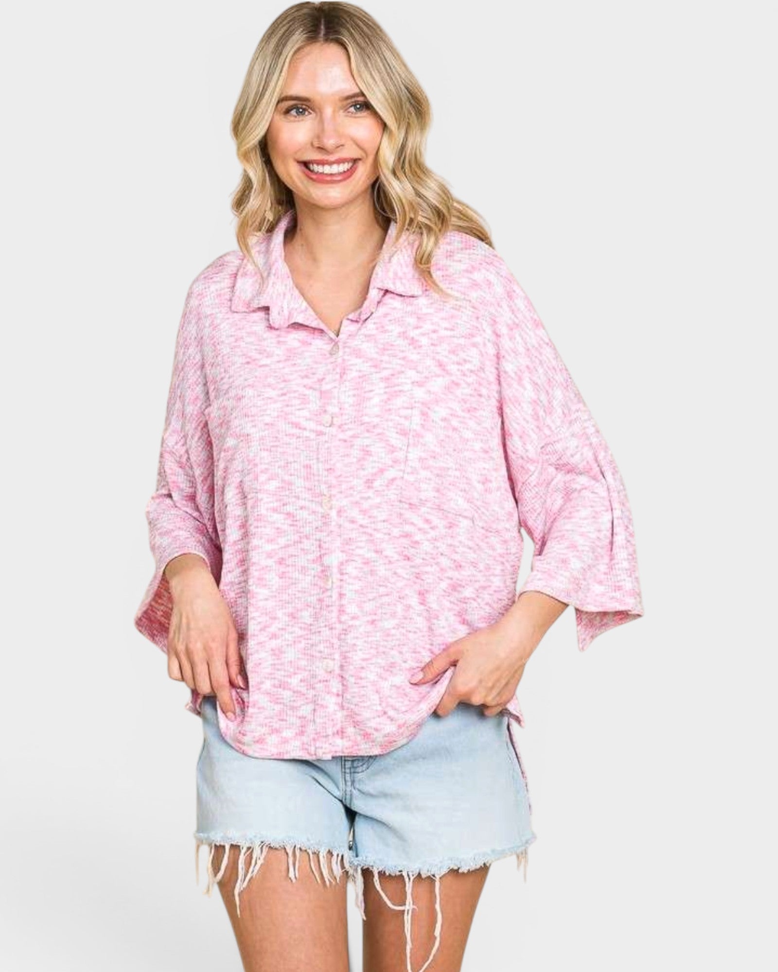 Woman wearing a pink patterned shirt and denim shorts on a white background