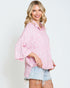 Woman wearing a pink patterned shirt and denim shorts on a plain background