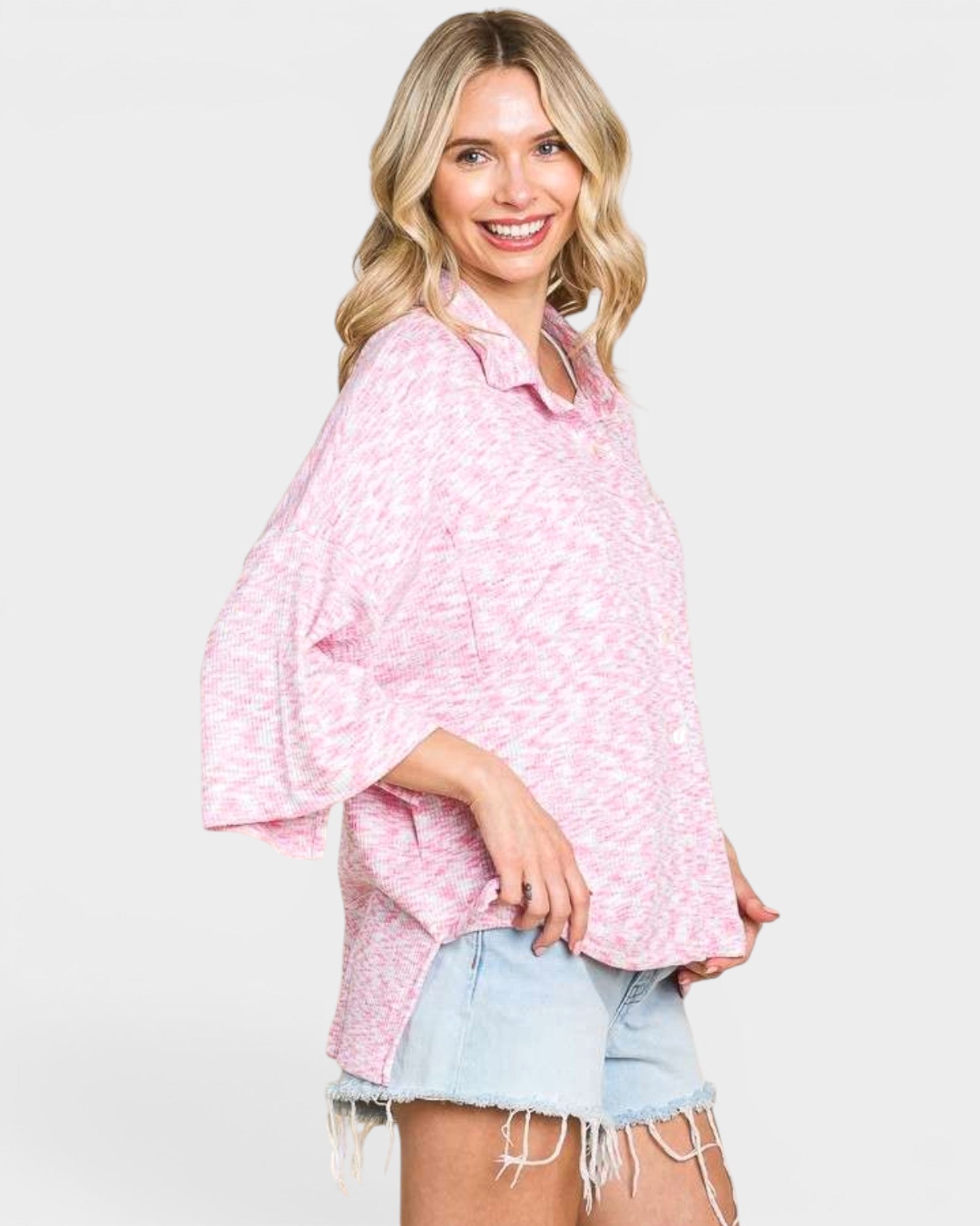 Woman wearing a pink patterned shirt and denim shorts on a white background