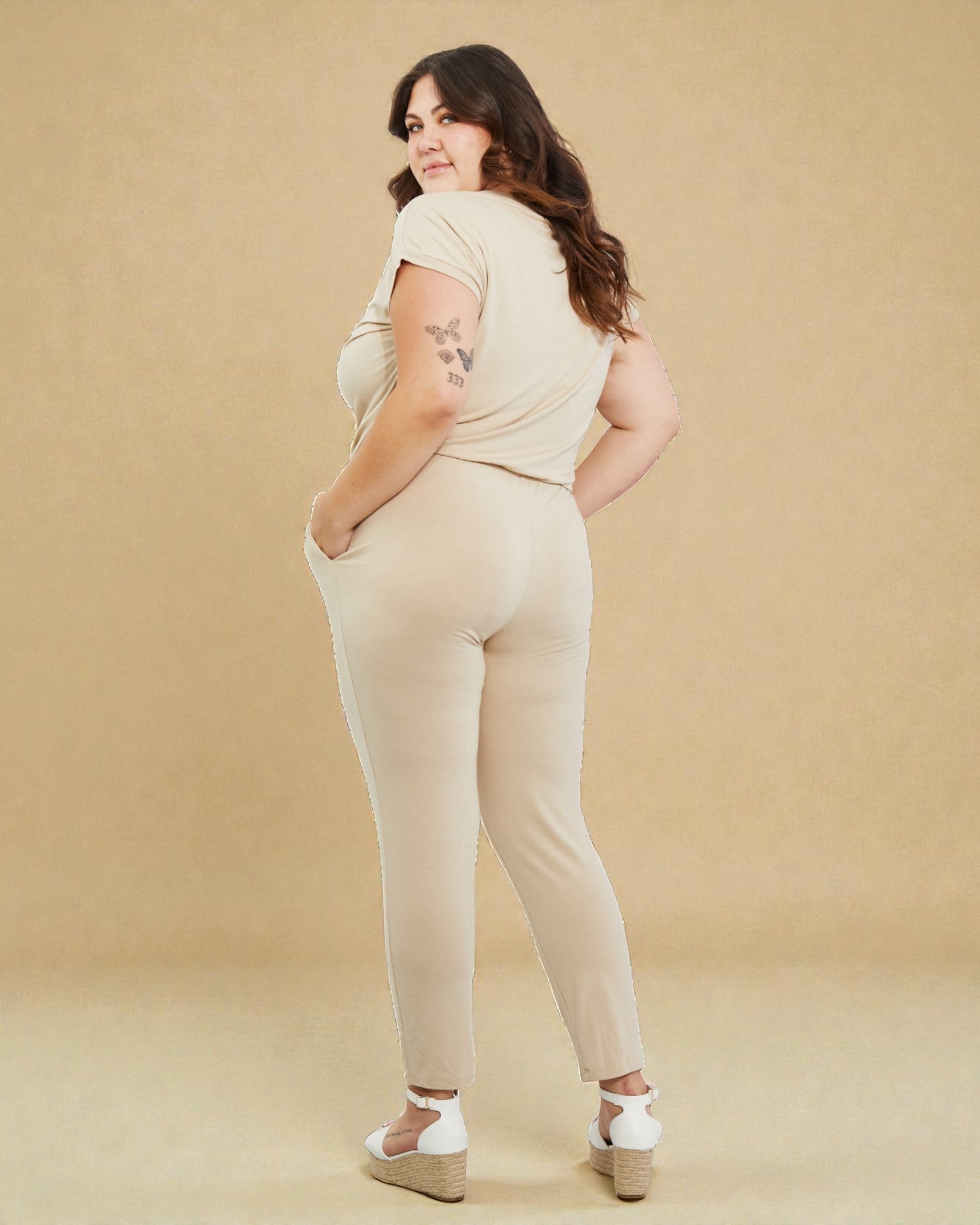 Woman wearing a beige jumpsuit against a beige background