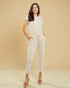 Woman wearing a beige jumpsuit against a beige background