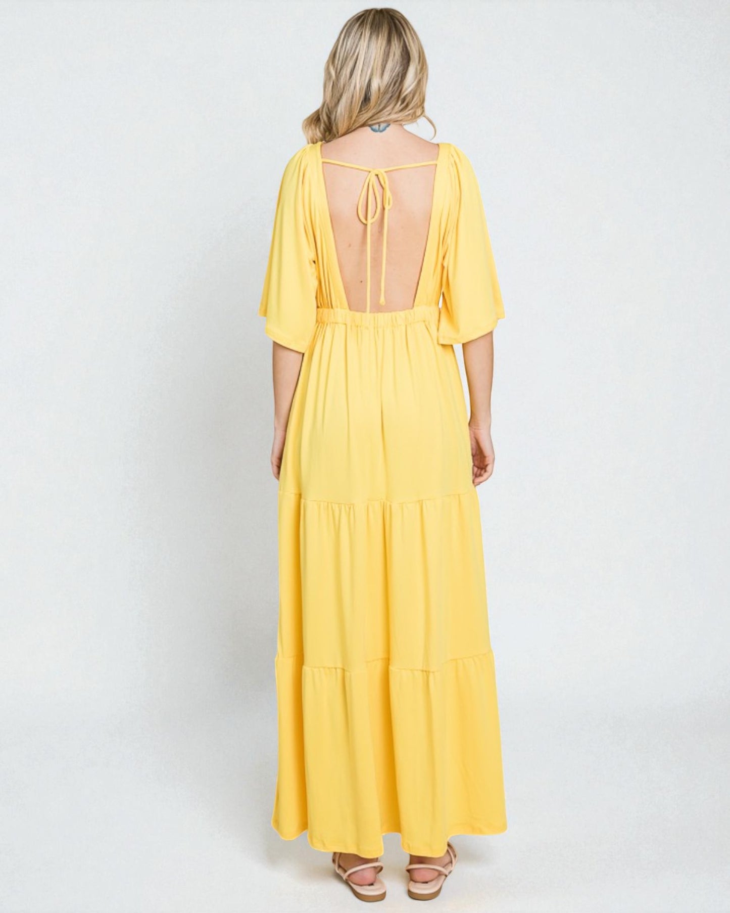 Woman wearing a yellow dress with a backless design on a white background