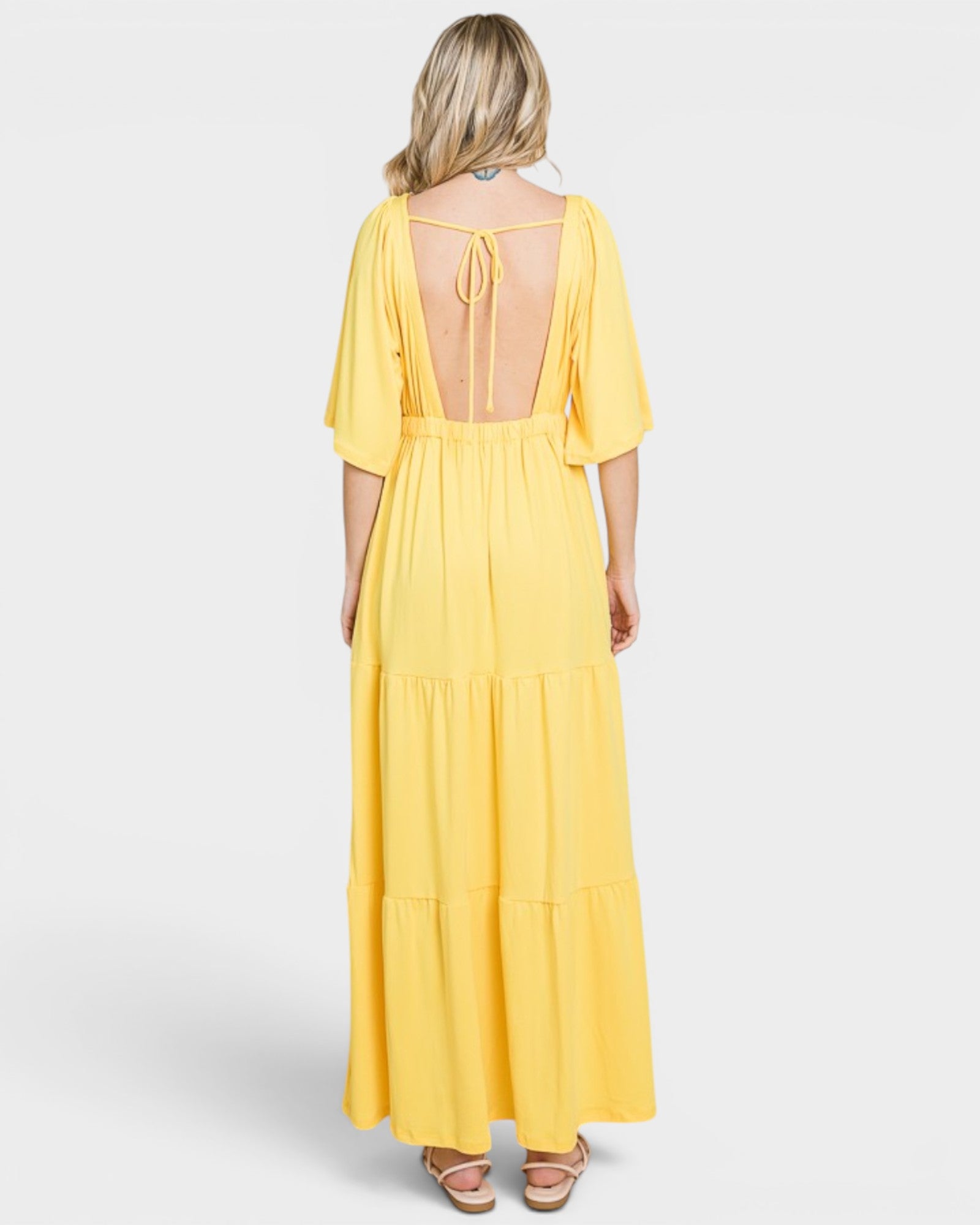 Yellow dress with open back worn by a person on a white background