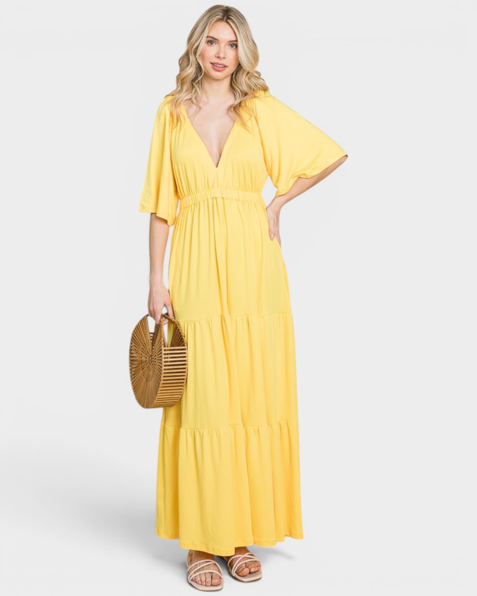 Woman wearing a yellow dress holding a straw bag on a white background