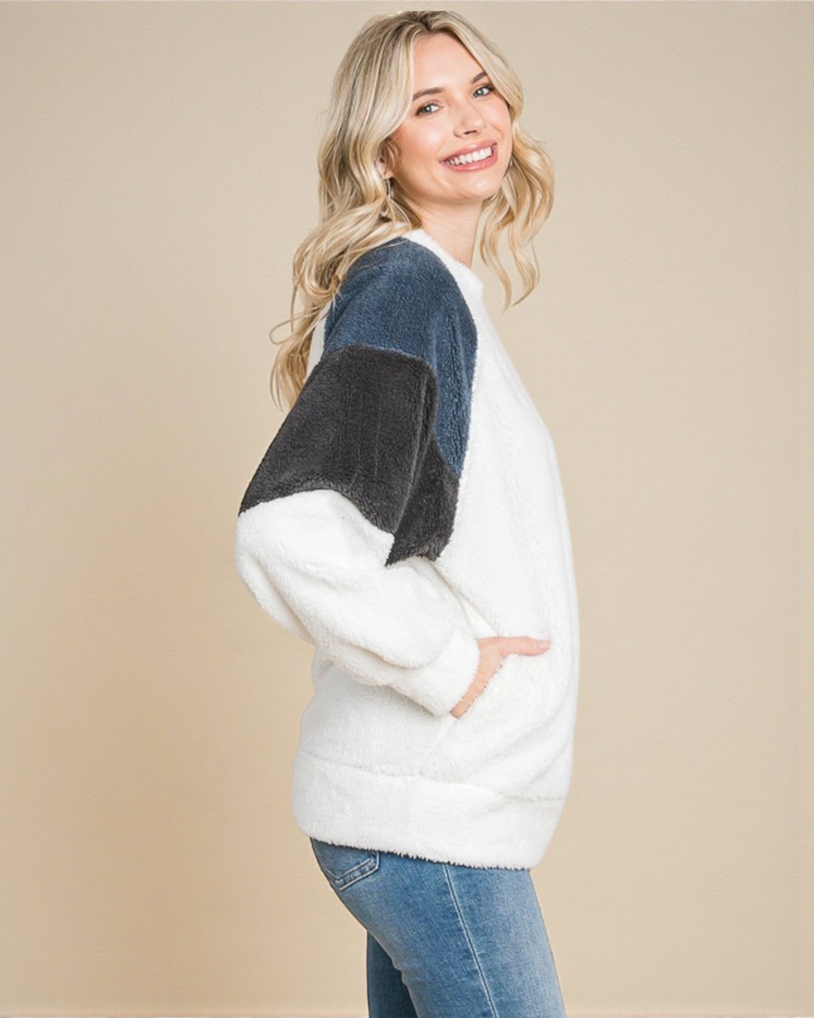 Woman wearing a white and blue sweater with a beige background