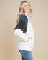 Woman wearing a white and blue sweater with a beige background