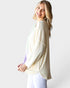 Woman wearing a cream cardigan over a light blue top on a white background