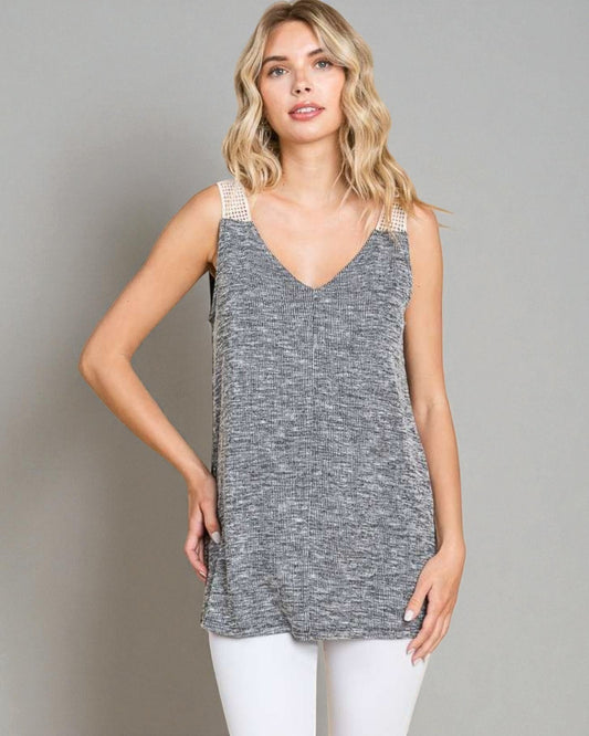 Woman wearing a gray tank top with white trim on a plain background