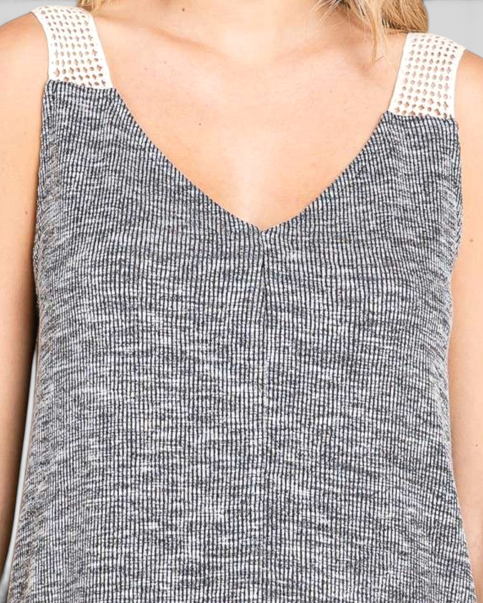 Close-up of a sleeveless top with a textured pattern and white lace trim on straps.