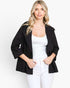 A woman modeling a black textured open-front jacket over a white tank top and white pants, photographed against a clean white studio background.