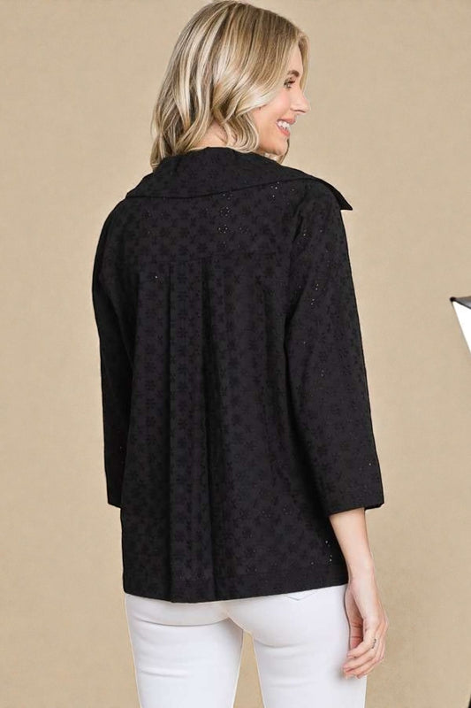 Woman wearing a black patterned jacket on a beige background