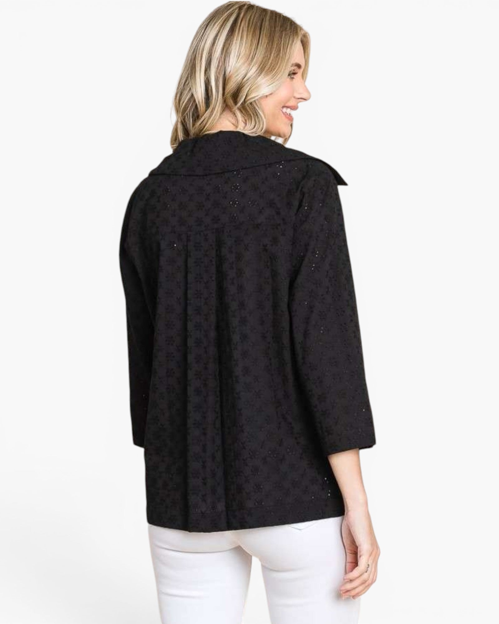 A woman shown from the back wearing a black patterned three-quarter sleeve jacket with white pants, photographed against a plain white studio background.