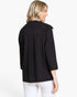 A woman shown from the back wearing a black patterned three-quarter sleeve jacket with white pants, photographed against a plain white studio background.