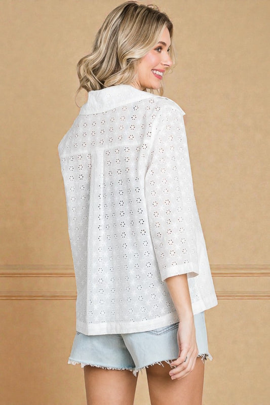 Woman wearing a white lace top and light blue shorts against a beige background