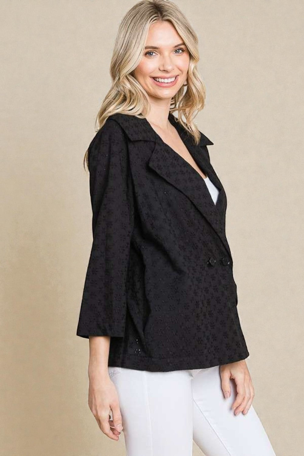Woman wearing a black patterned blazer over a white top on a beige background