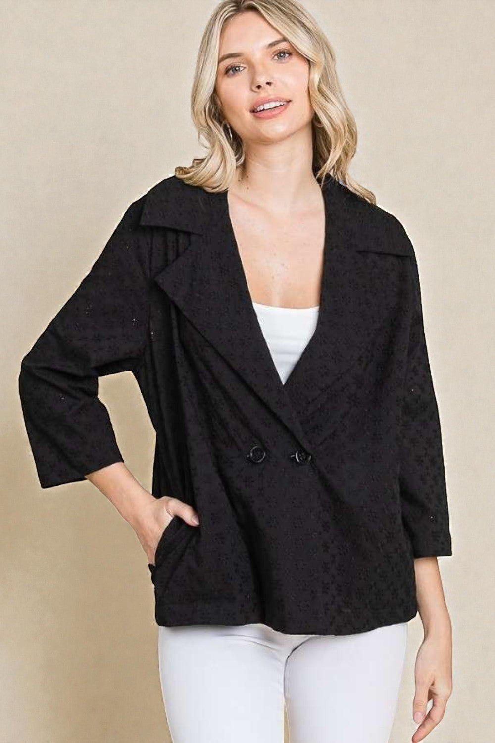 Woman wearing a black coat with a beige background