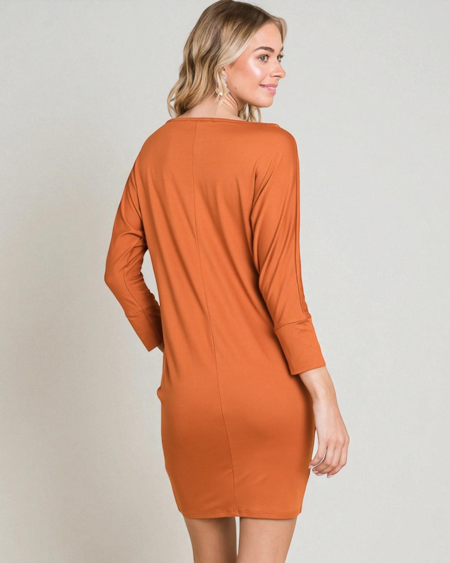 Woman wearing a rust-colored dress against a plain background