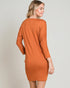 Woman wearing a rust-colored dress against a plain background