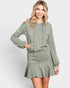 Woman wearing a green hoodie and skirt set on a white background