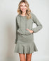Woman wearing a green hoodie and skirt set on a plain background