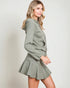 Woman wearing a green hoodie and skirt set against a plain background