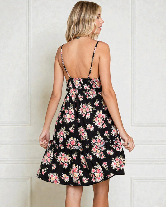 Woman wearing a black floral dress against a white wall