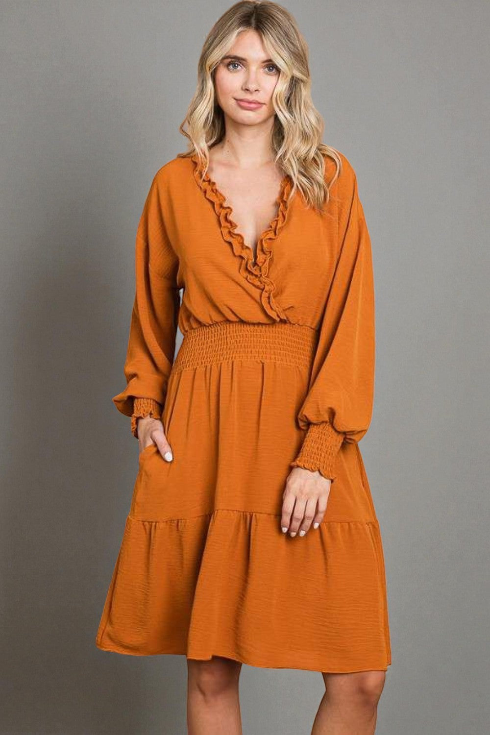 Woman wearing a rust-colored dress against a gray background