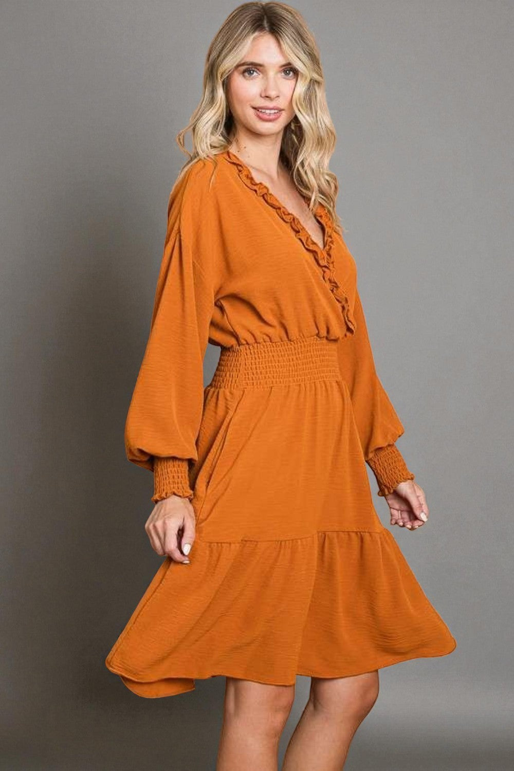 Woman wearing an orange dress against a gray background