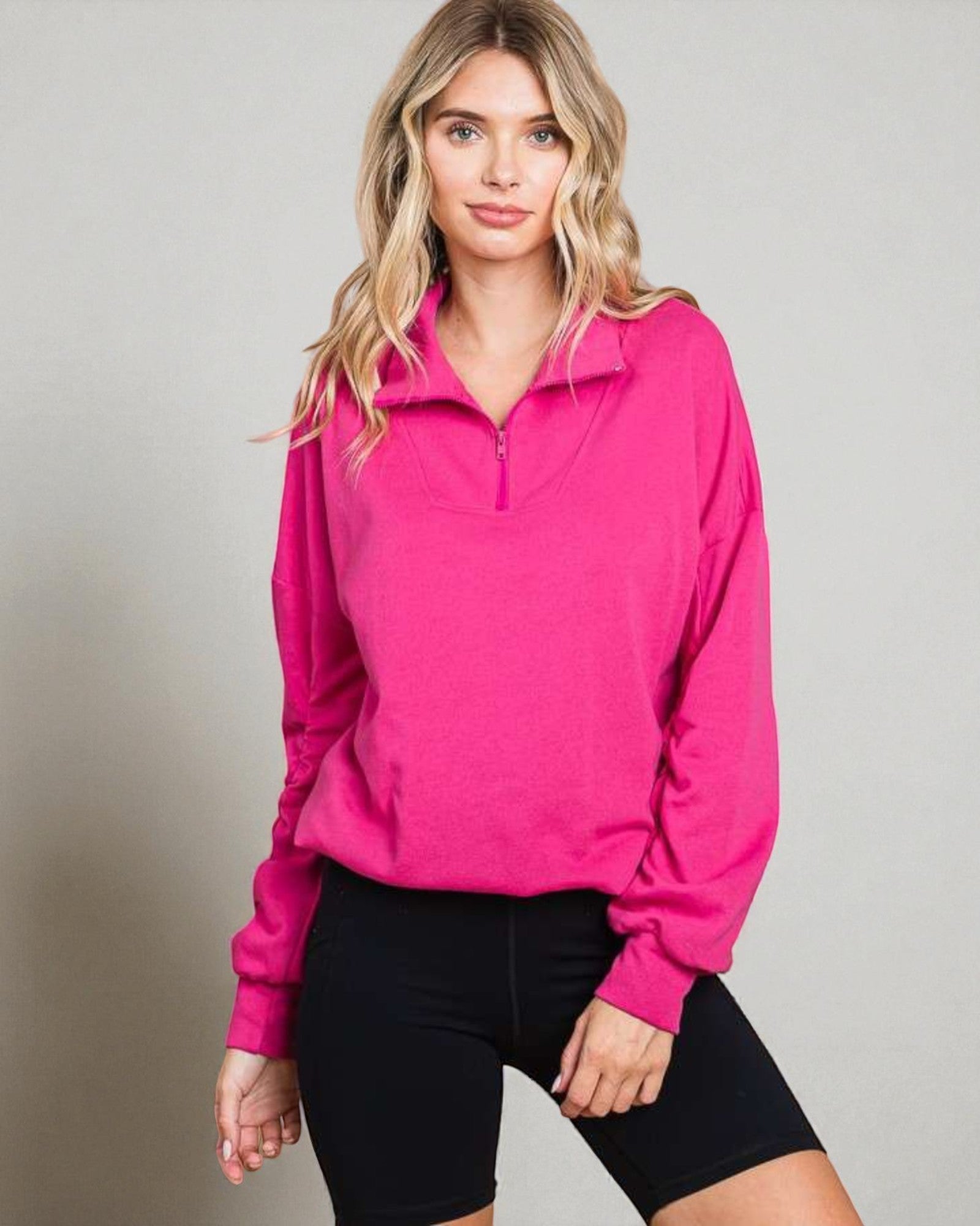 Woman wearing a bright pink long-sleeve athletic top against a neutral background