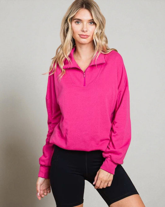 Woman wearing a bright pink long-sleeve athletic top against a neutral background