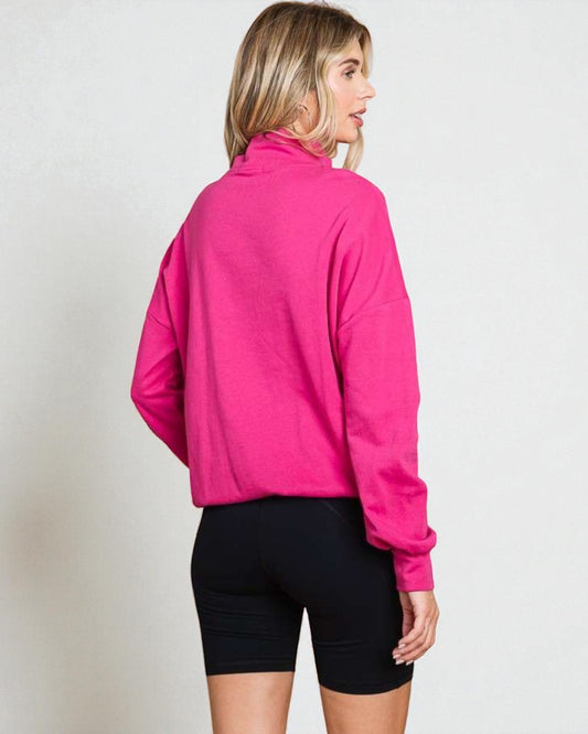 Person wearing a bright pink jacket and black shorts on a plain background