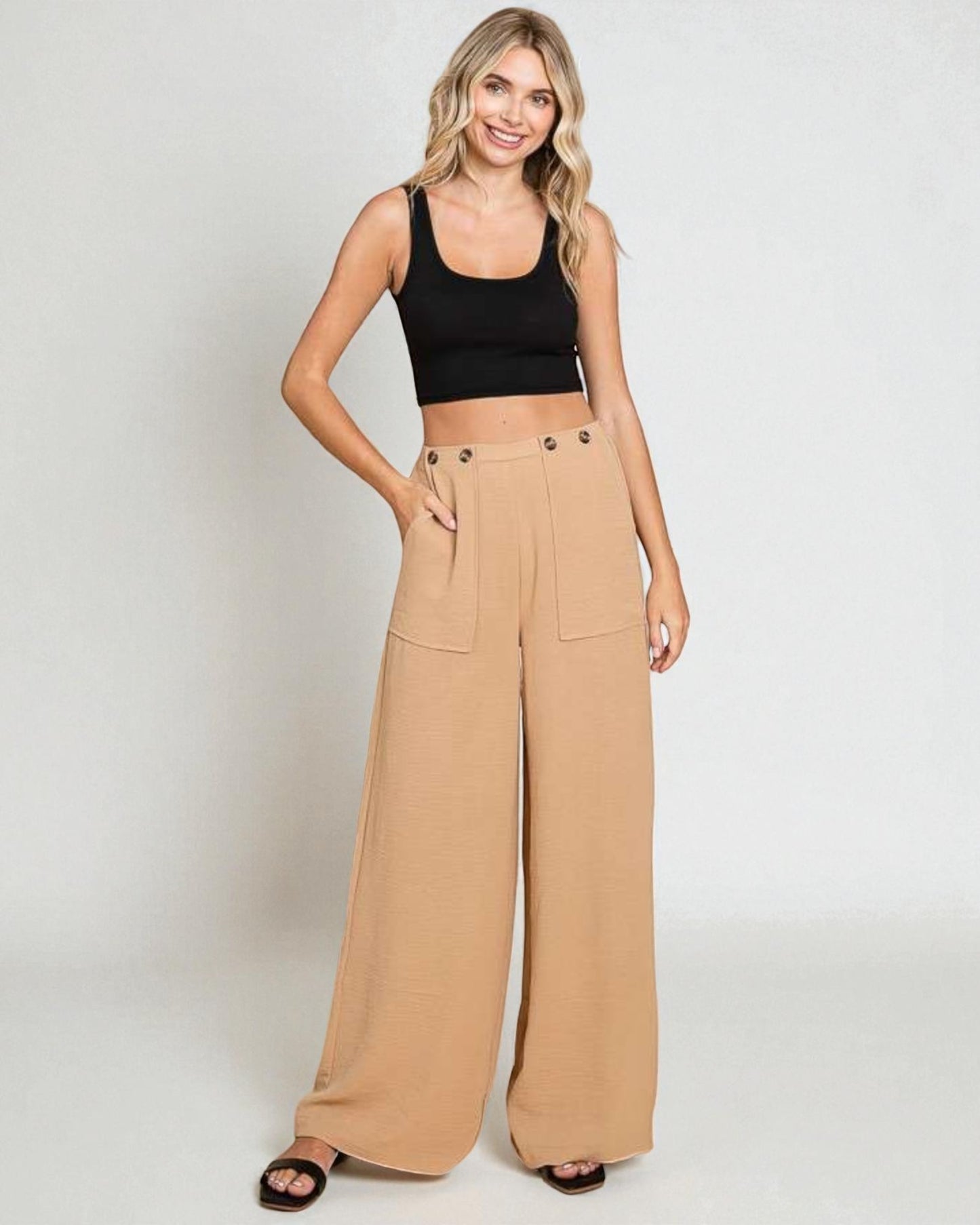 Woman wearing a black top and beige wide-leg pants on a white background