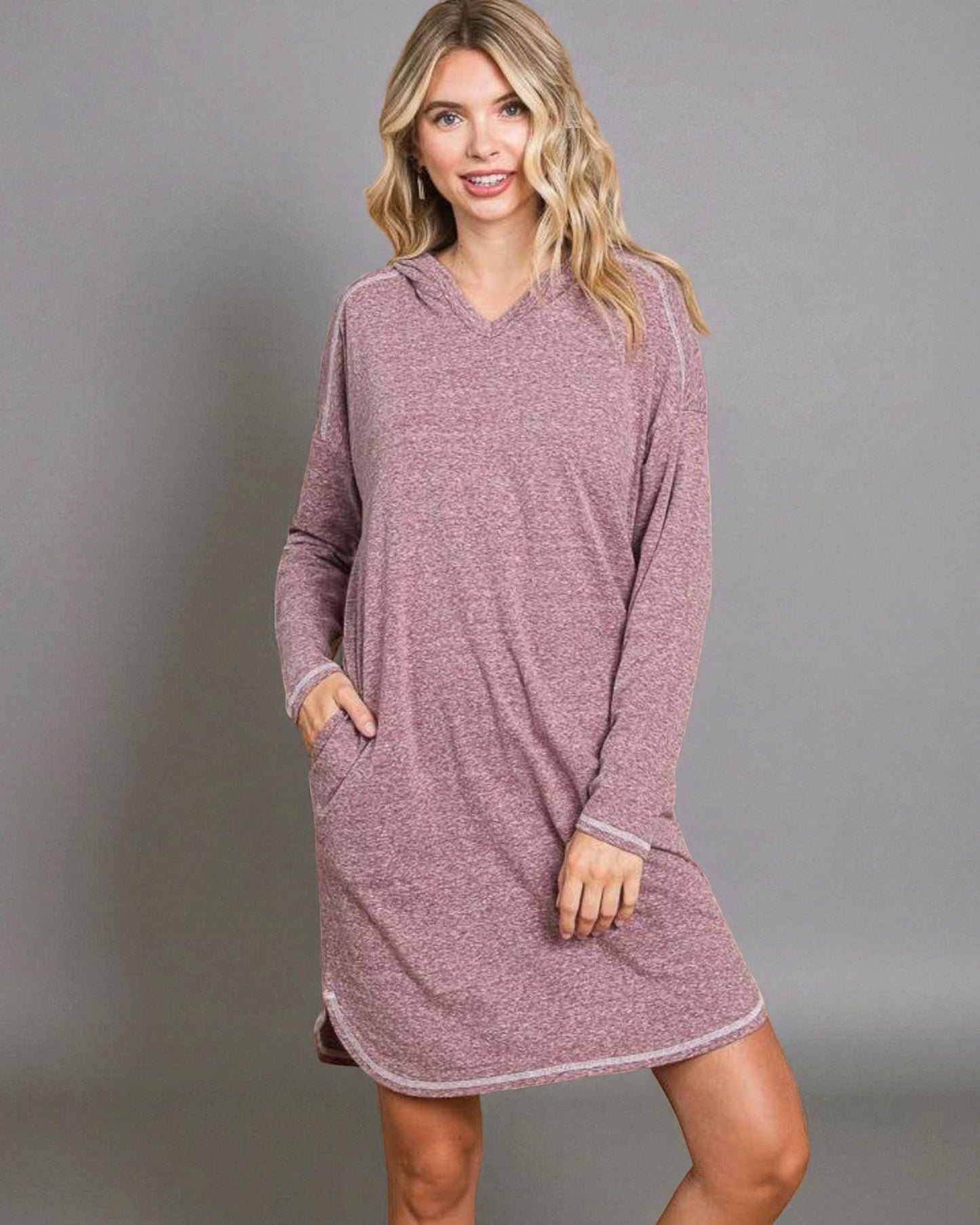 Woman wearing a mauve hooded dress against a gray background