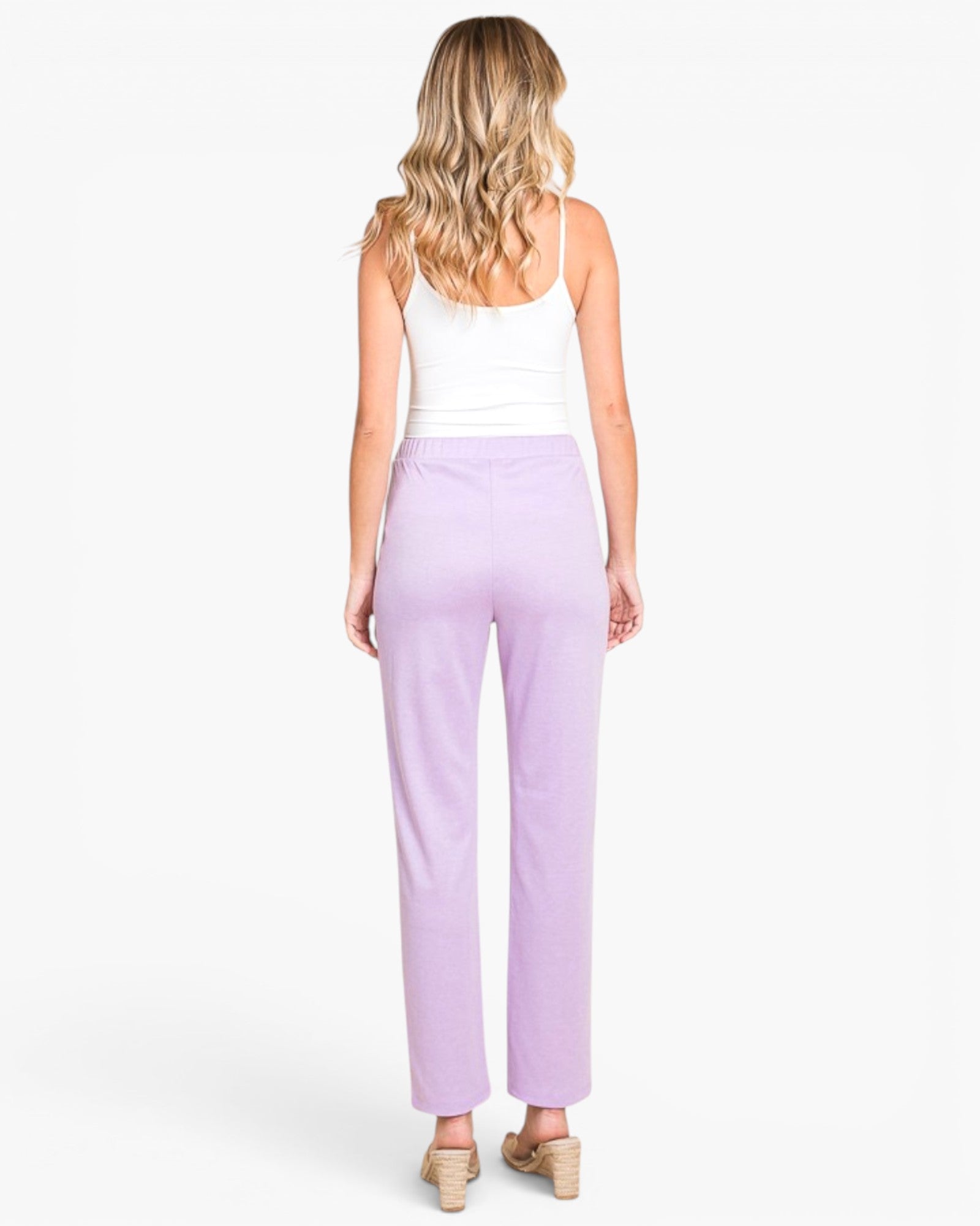 A woman shown from the back wearing lavender wide-leg cropped pants, a white tank top, and beige wedge sandals against a plain white studio background.