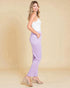 Woman wearing a white top and lavender pants on a beige background