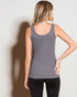 Woman wearing a gray tank top and black pants against a plain background